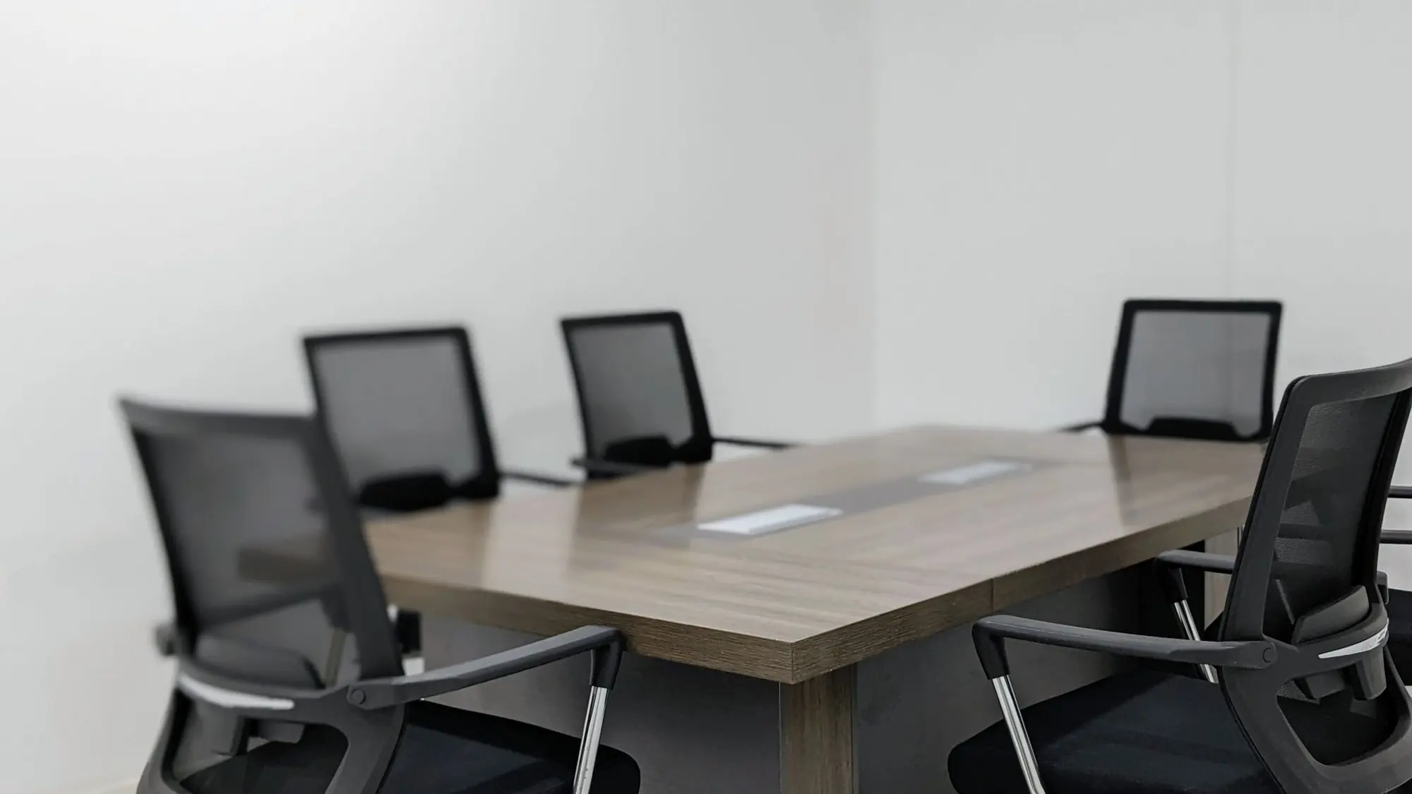 Sala de reuniones vacía con una mesa de madera y sillas negras