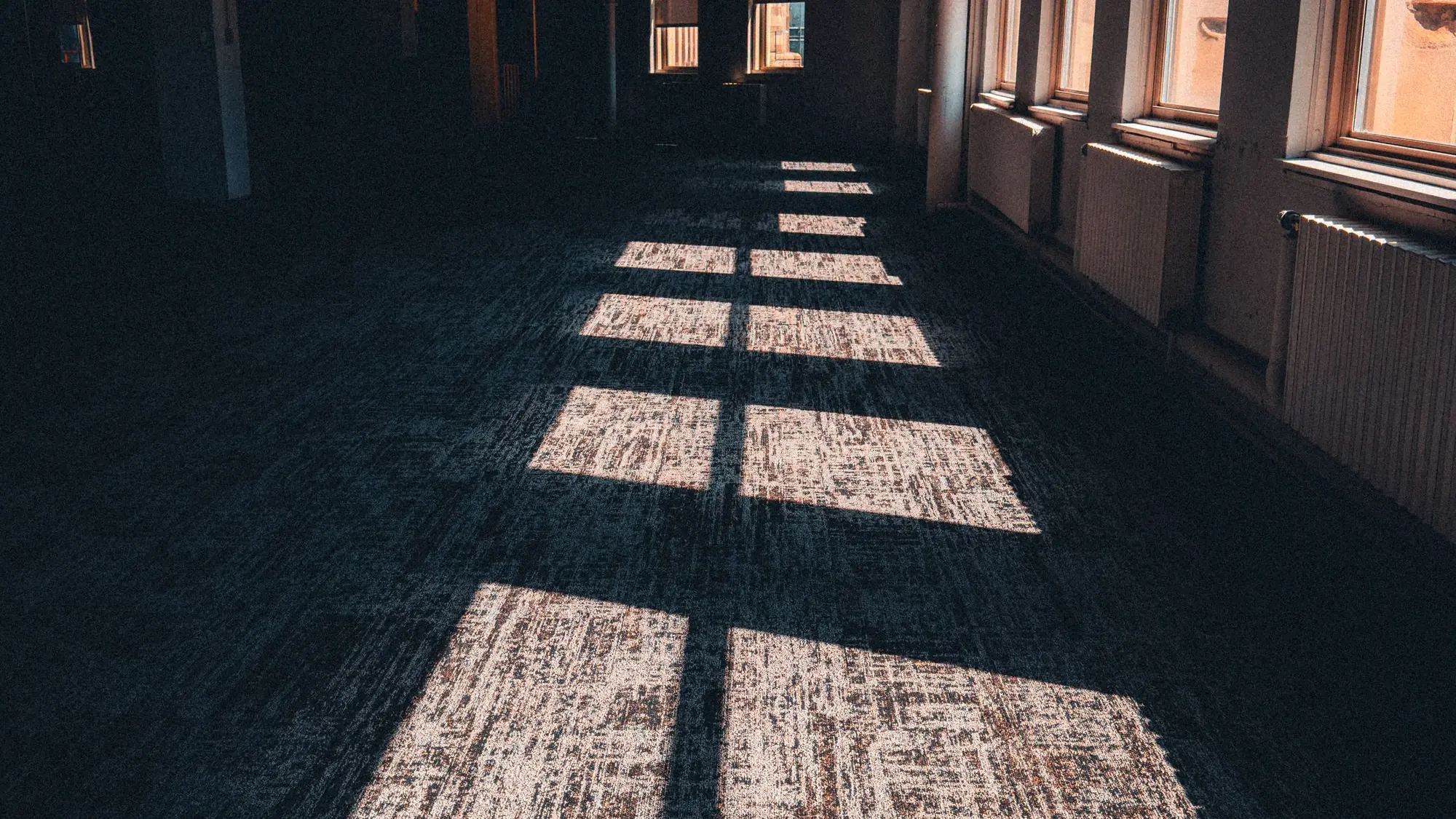 Pasillo de oficina vacío con el sol dibujando rectángulos de luz sobre el suelo